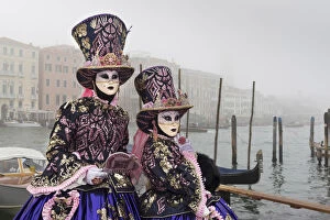 Two women in costume at Carnival time near Grand canal in mist, Venice, Veneto, Italy