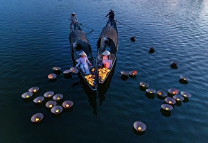 Candle Prints: Women laying floating lanterns on the Perfume River at dusk, Hue, Central Vietnam