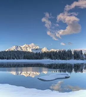 Woods and snowy peaks are reflected in the clear water of PalA AA┬╣ Lake Malenco Valley