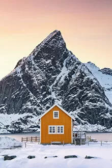 Typical Gallery: Yellow Rorbu with majestic Olstind peak covered with snow on background, Sakrisoy, Reine, Nordland
