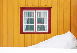 Wooden House Prints: Yellow wall and red windowframe of old wooden house in the snow