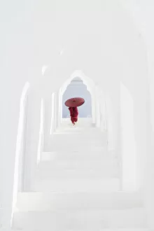 Myanmar Gallery: A young Buddhist monk holding a red umbrella walks up the steps in Hsinbyume Pagoda