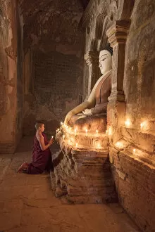 Images Dated 30th March 2017: Young Buddhist monk prays in front of a statue of Buddha in a temple in Bagan, Myanmar