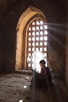 Young Buddhist monk reads by a window in a temple in Bagan, Myanmar Young Buddhist monk reads by a window in a temple in Bagan, Myanmar