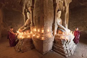 Sacred Prints: Young Buddhist monks pray in front of a statue of Buddha in a temple in Bagan, Myanmar