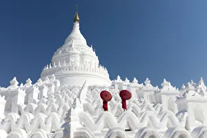 Umbrella Gallery: Two young Buddhist monks stand on the white walls of Hsinbyume Pagoda holding red
