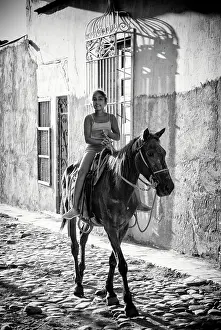Trinidad Prints: Young Cuban girl riding her horse on a cobbled street in the old sugar town of Trinidad (a UNESCO World Heritage Site)
