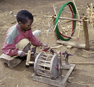 Images Dated 5th February 2009: A young Dorze boy winds cotton onto a bobin for his father