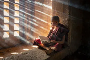 A young monk reading by a window inside a temple, UNESCO, Bagan, Mandalay Region, Myanmar