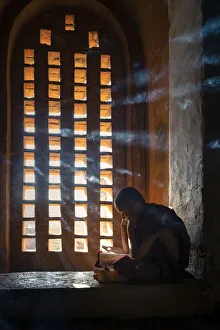 Side View Prints: A young monk studying by a window inside a temple, UNESCO, Bagan, Mandalay Region
