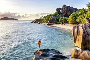 Model Released Gallery: A young woman admires the sunset at Anse Source d Argent, La Digue, Seychelles, Africa