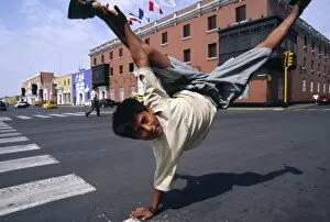 Performing Collection: A youth performs an armstand on the streets of Trujillo